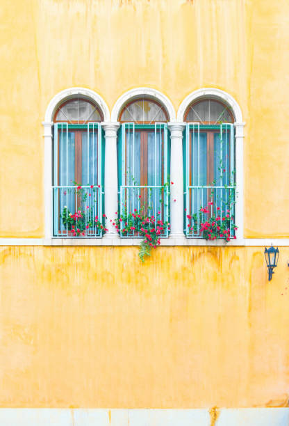 istock Three arch windows with flowers in yellow Italian stucco wall 1208438090
