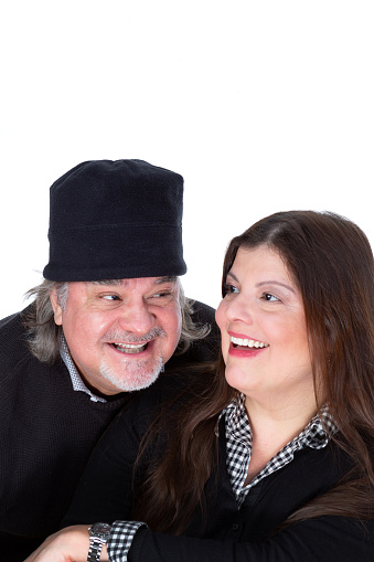 Couple poses for a studio portrait over white background. they are looking at each other smiling.