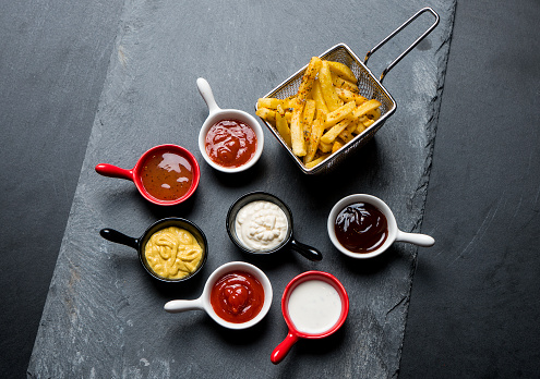 High angle view of several bowls with delicious sauces and home fries potato