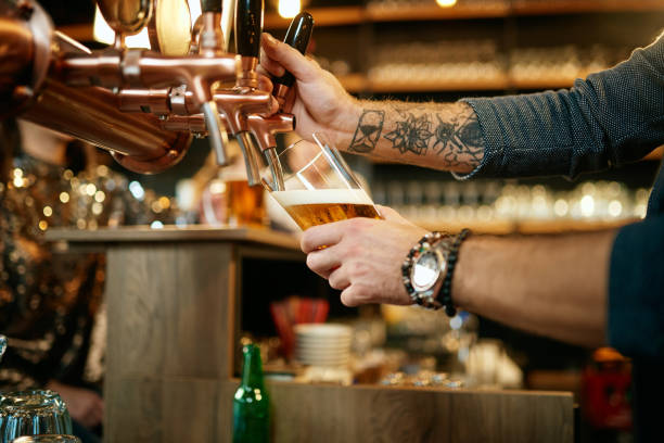 istock Tattooed caucasian barman pouring beer while standing in pub. Selective focus on hand. 1208443163