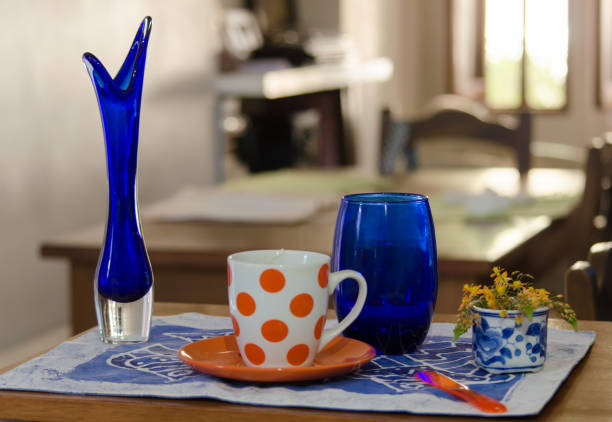 Wooden table with orange polka dot cup and classic blue objects. Horizontal shot .