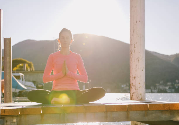 istock Woman performs yoga moves on lakeside pier 1208446482