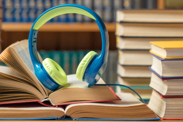 istock Audio book concept - headphones with books at the library 1208448421