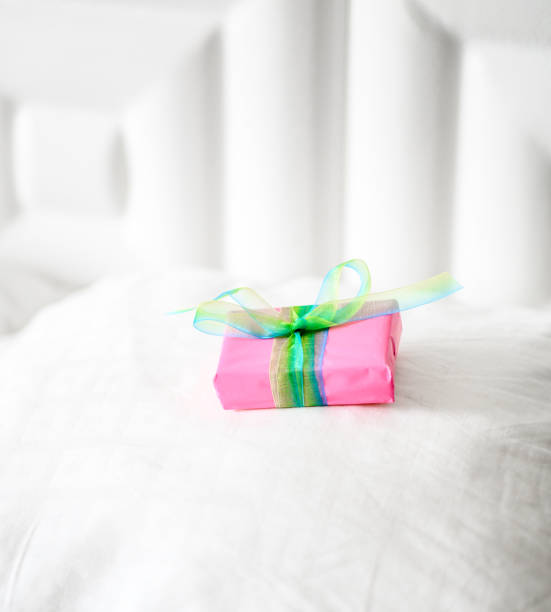 istock Special wrapped gift placed on a clean white bed, surprise present 1208451354