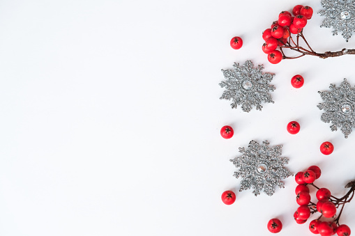 Christmas winter composition. Rowan berry and silver snowflakes on white background. Top view, flat lay