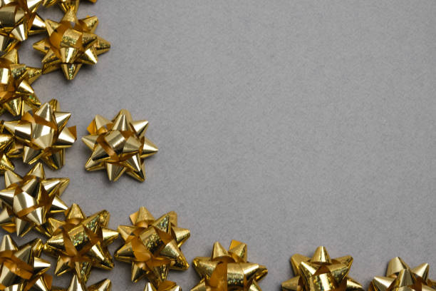 istock Golden bows on gray table top view. Flat lay composition for wedding, Christmas or birthday 1208455743