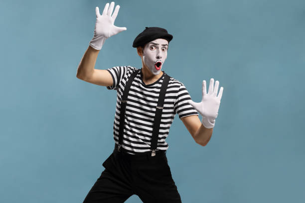 Pantomime man touching an imaginary glass Pantomime man touching an imaginary glass isolated on blue background pantomime stock pictures, royalty-free photos & images