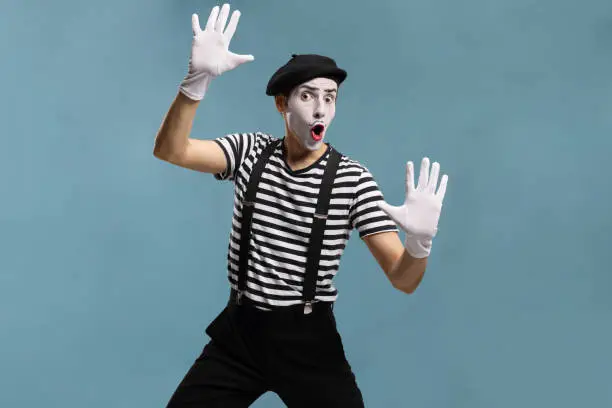 Pantomime man touching an imaginary glass isolated on blue background