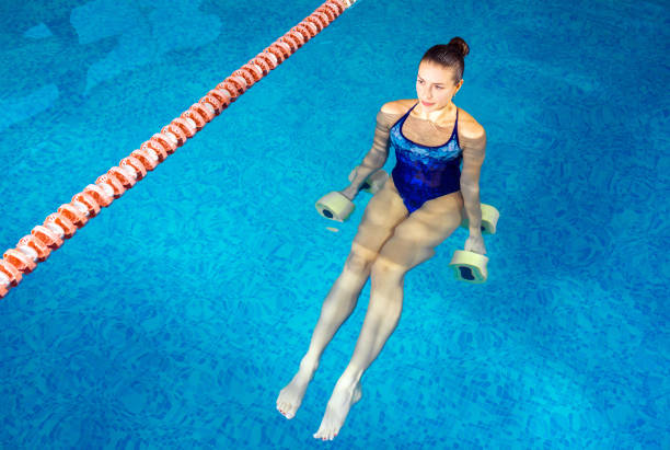 istock Young woman doing water aerobics in indoor pool, sporting concept 1208457194