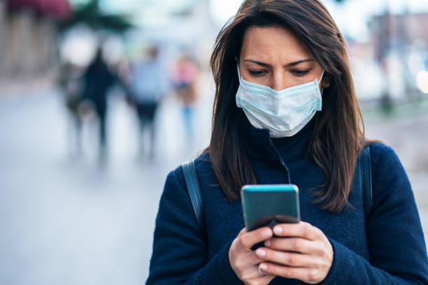 Woman with face protective mask Portrait of young woman on the street wearing  face protective mask to prevent Coronavirus and anti-smog and using smartphone avian flu virus photos stock pictures, royalty-free photos & images