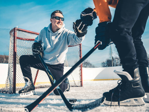 vater und sohn spielen hockey im freien - ice skating ice hockey child family stock-fotos und bilder