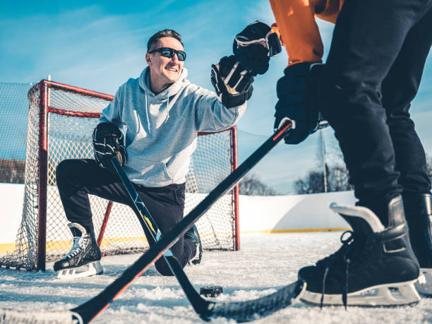 father and son playing hockey outdoors - ice skating ice hockey child family imagens e fotografias de stock