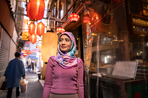Asian woman in hijab walking in Japanese Izakaya alley