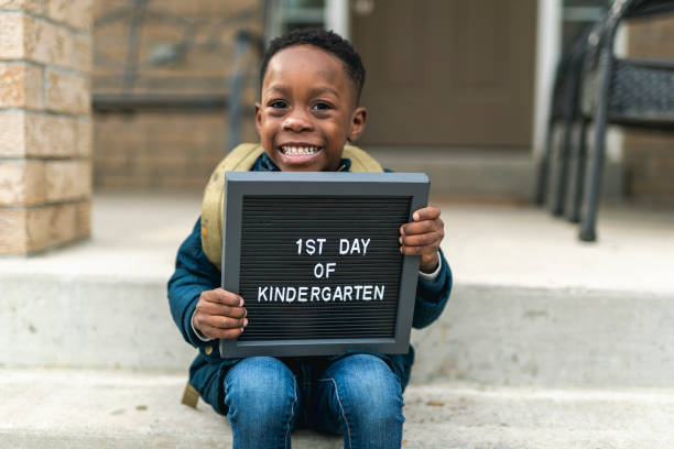 un chico lindo sosteniendo un primer día de signo de jardín de infantes - back to school fotos fotografías e imágenes de stock