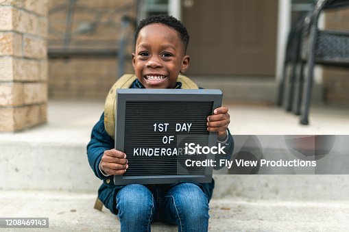istock A cute boy holding up a first day of kindergarten sign 1208469143