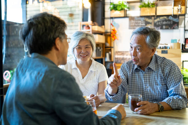 istock Man sitting in cafe with his parents and talking 1208469261