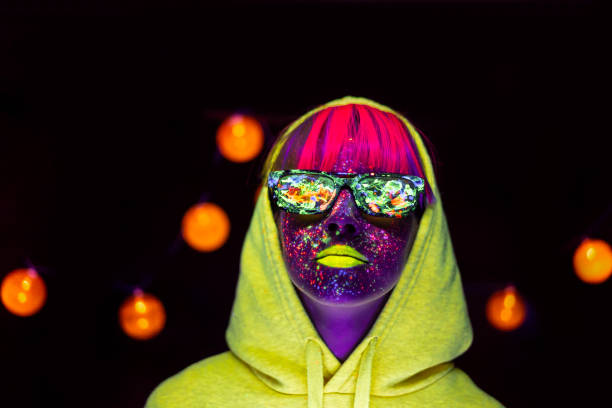 istock Woman with glowing makeup and sunglasses in black light 1208469409