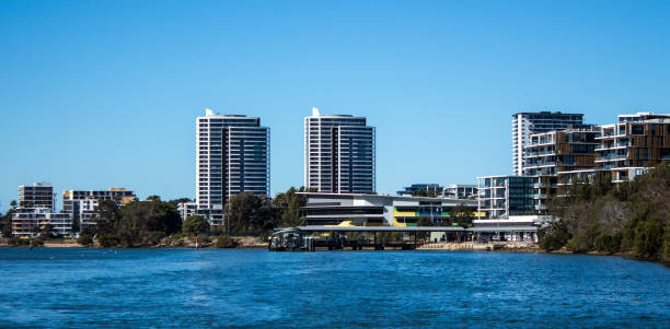 istock Large waterfront apartment condominiums in suburban community on harbour with tree lined walkway, blue sky in background 1208475376