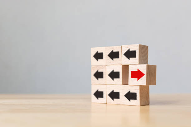 istock Wooden block with red arrow facing the opposite direction black arrows, Unique, think different, individual and standing out from the crowd concept 1208480231