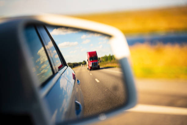 Red semi-truck reflected on car side mirror