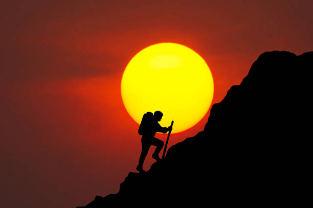 Man climbing up a mountain. while climbing the challenging route on the cliff on the colorful down sky background. rock climber