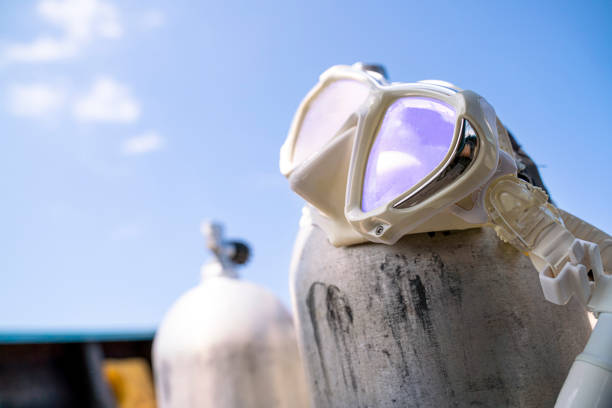 A white diving mask hanging on the oxygen tank for scuba diving on the boat with blue sky background shallow focus