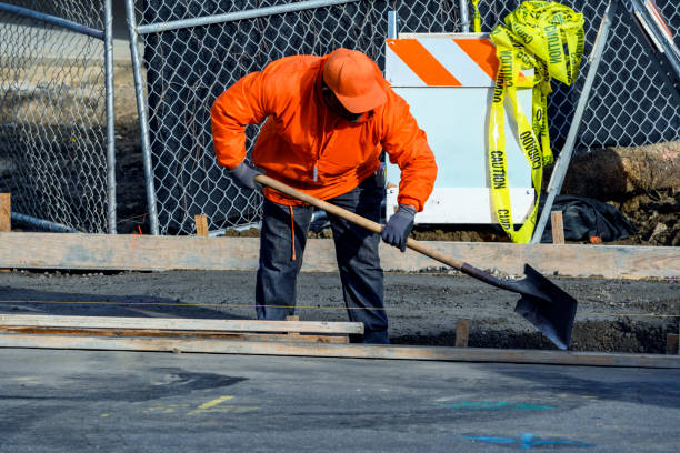California, USA - January 15, 2020: Construction worker installing a new sidewalk, curb and storm drainage gutter for a new house construction.