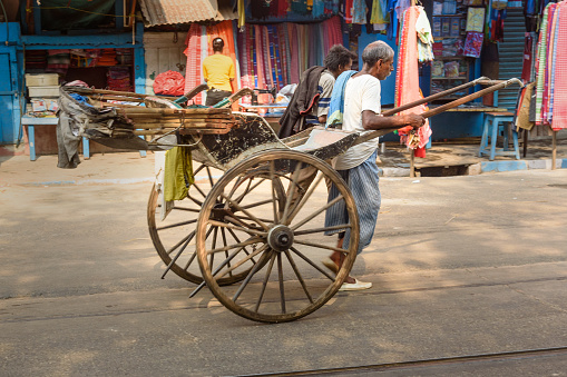 Kolkata, India - March 13, 2019: Man rickshaw puller is pulling his hand rickshaw on the street