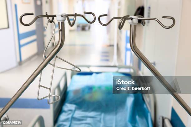 A Vacant Hospital Bed In Hallway With Dropper Stands Stock Photo - Download Image Now
