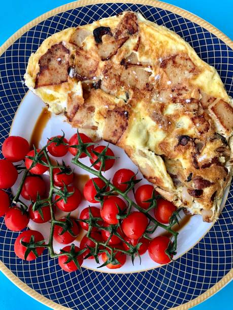 imagen de tortilla de patata española doblada servida en plato con tomates cherry de vid y vinagre balsámico, vista elevada - tomatoes on vine fotografías e imágenes de stock