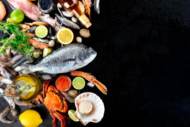 fond de poissons et de fruits de mer avec l’espace de copie, un projectile supérieur plat de lay. daurade, crabe, calmar, pétoncles sur noir avec une place pour le texte - prepared shellfish seafood lobster ice photos et images de collection