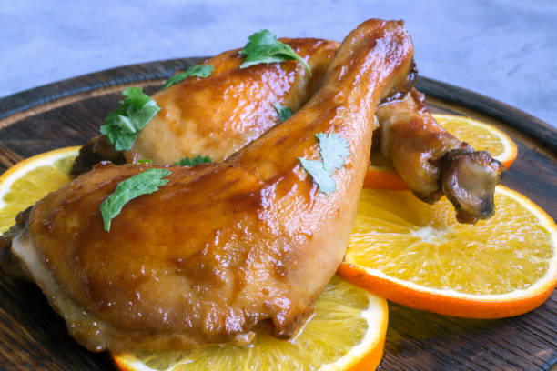 istock chicken legs glazed in honey sauce with oranges. 1208506757