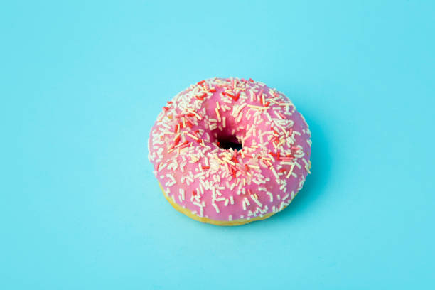 istock Donut (doughnut) of different colors on a blue background with multi-colored festive sugar sprinkles. Holiday and sweets, baking for children, sugar concept 1208507721
