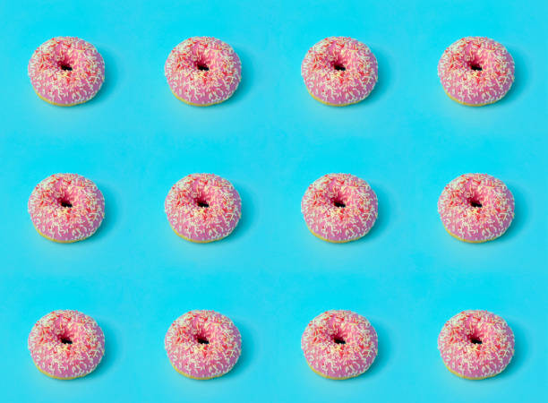 istock Donuts (doughnuts) of different colors on a blue background with multi-colored festive sugar sprinkles. Holiday and sweets background. Minimal concept 1208507725
