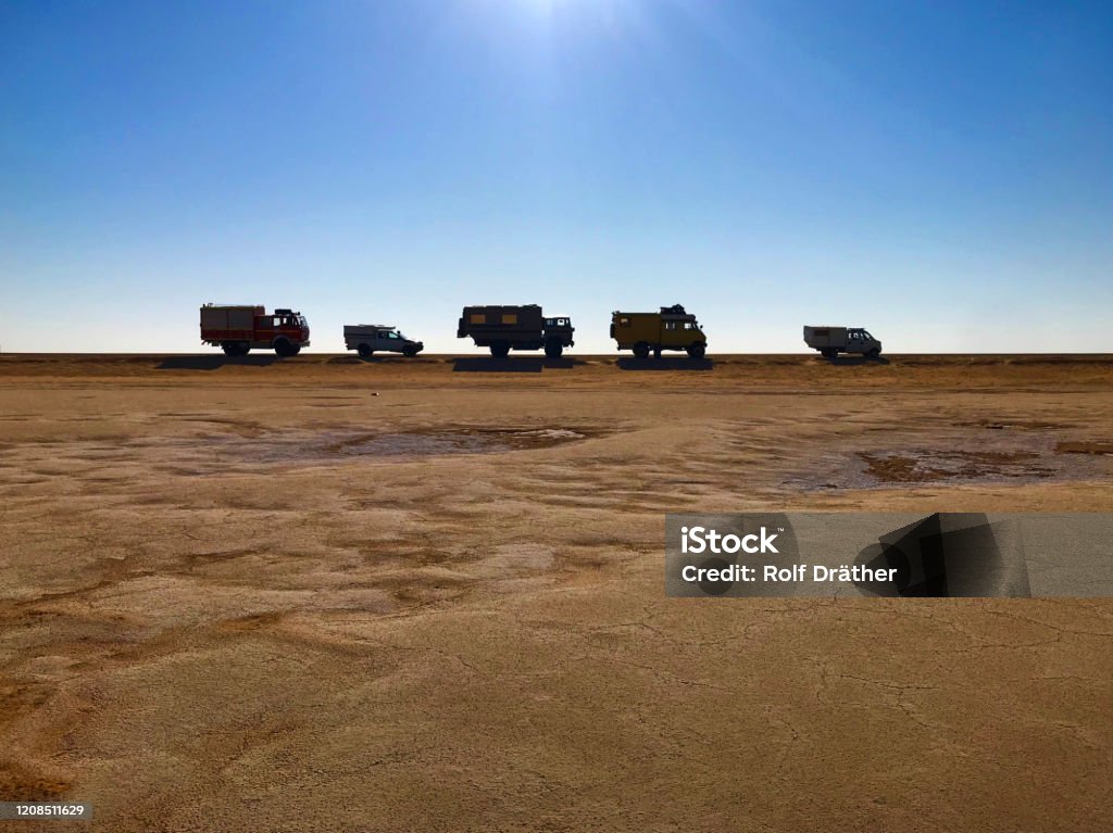 Side view of 5 cars standing in a line at a flat with blue sky above and sunbeam Photo shoot of some offroad vehicles parking at the road of the Chott el Djerid, salt lake, Tunisia Car Stock Photo