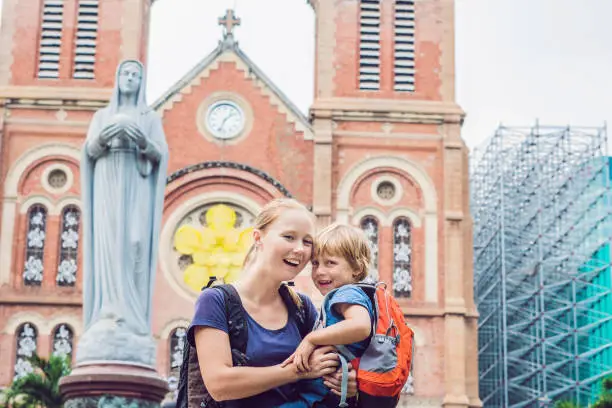 Photo of Mom and son in the background Notre dame de Saigon Cathedral, build in 1883 in Ho Chi Minh city, Vietnam