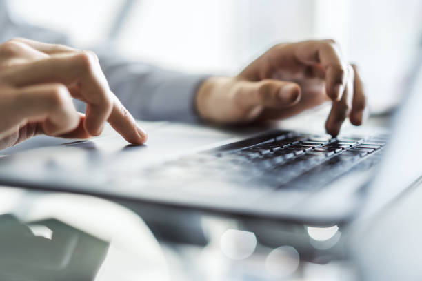 uomo d'affari che digita sulla tastiera del laptop in un ufficio soleggiato, concetto di business e tecnologia. primo tempo - track pad foto e immagini stock