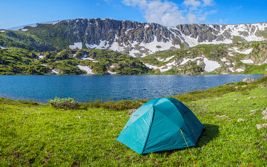 Summer holidays in the mountains, a tent on the shore of a mountain lake