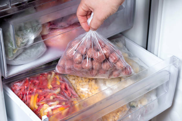 istock Man putting plastic bag with meatballs in refrigerator with frozen vegetables 1208513073
