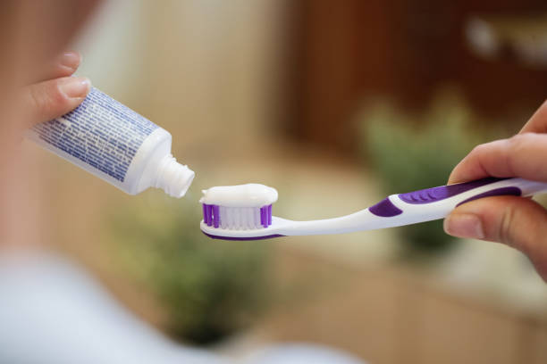 istock Close-up of woman applying toothpaste on a toothbrush. 1208514503