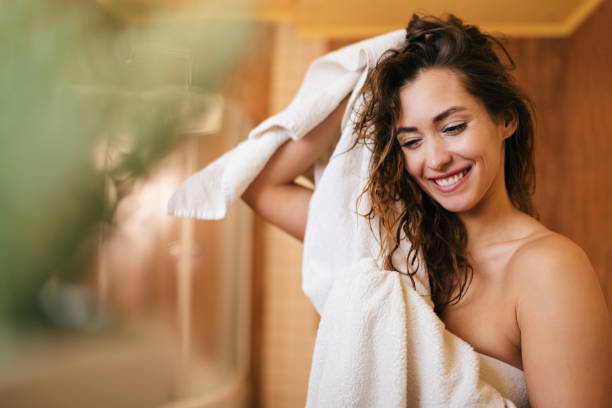 belle femme heureuse séchant ses cheveux avec une serviette dans la salle de bains. - cheveux ou poils photos et images de collection