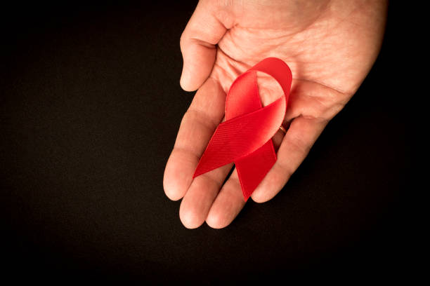 istock Red aids ribbon in human hand on dark background. Close up. Empty space text. 1208517716