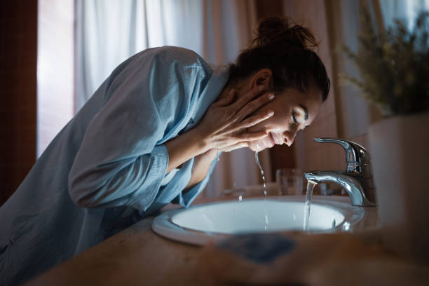 mujer sonriente lavándose la cara por la noche. - rutina fotografías e imágenes de stock