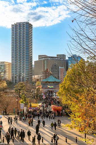 ueno, japan - january 02 2020: High angle view on the Kaneiji Temple in Ueno park with people walking in peddlers or carnies or Tekiya japanese food stands aisles at sunset, Tokyo, Japan.