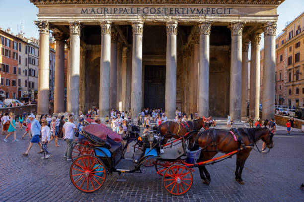 Hors drawn carriage in front of the temple of Pantheon in Rome. The Pantheon is a former Roman temple, now a church, in Rome, Italy. It's located in Piazza della Rotonda. People are tourists enjoying the ancient city.