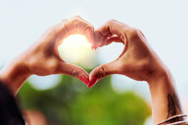Cropped shot of an unrecognizable woman making a heart shape with her hands outdoors