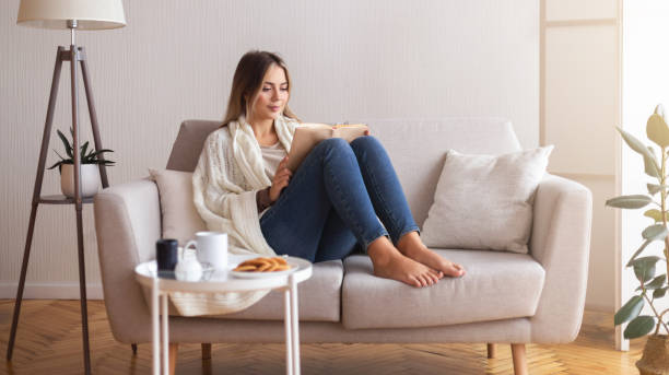Millennial woman reading book at home interior