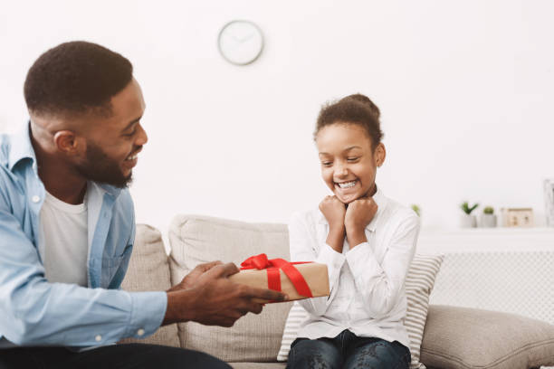 urodzinowa dziewczyna. tata robi prezent dla córki - male men black african descent zdjęcia i obrazy z banku zdjęć