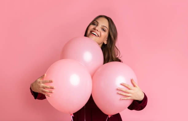 istock Playful Young Girl Cuddling Three Balloons And Sincerely Smiling 1208522484