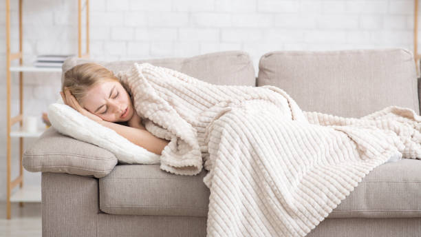 istock Afflicted girl laying on couch wrapped in blanket, feeling bad 1208522690